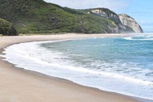 A beautiful beach with sea on one side and green hills on another