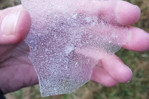 A hand holding some ice illustrating how cold it was during the last night's camping